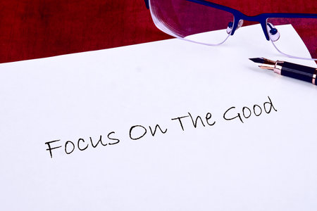 A handwritten message emphasizes the importance of staying positive and focusing on the good in life. Glasses and a pen lie beside it, ready for inspiration.の写真素材