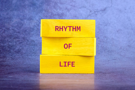 Three bright yellow blocks are stacked, each bearing part of a phrase. The message spells out a powerful mantra RHYTHM OF LIFE in bold, red letters against a textured backdropの写真素材