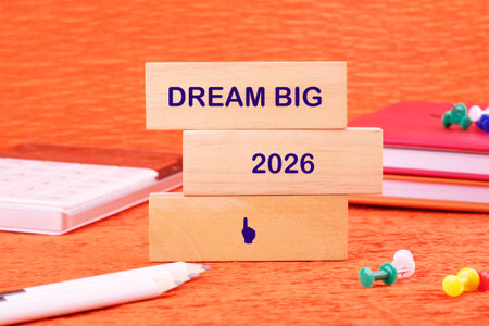 Colorful wooden blocks display the words dream big and the year 2026 against a bright orange...