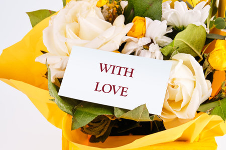 A vibrant arrangement of fresh flowers, including white roses and colorful blooms, is complemented by a note saying with love, conveying deep emotions and warmth.の写真素材