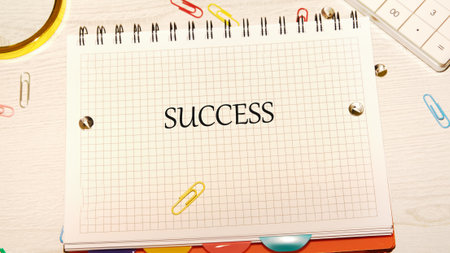 A grid notebook lays open on a desk, prominently displaying the word success in bold letters....