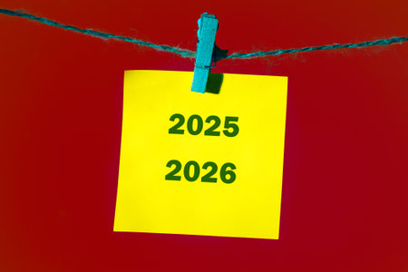 Colorful sticky notes with the years 2025 and 2026 are clipped to a string against a vibrant red backdrop, suggesting organization and future planning.の写真素材