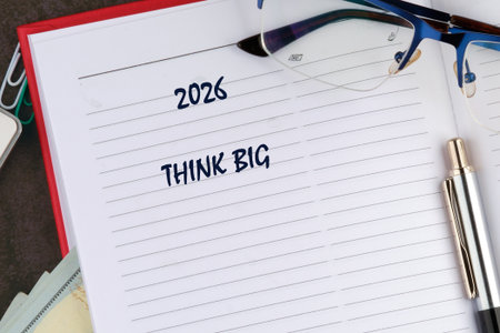 A planner opened to a new year page features the phrase think big prominently displayed. Surrounding it are glasses and a pen, symbolizing focus on future aspirations and ambitions.の写真素材