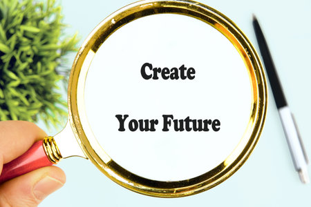 A hand holds a magnifying glass focusing on the words create your future, symbolizing clarity and...