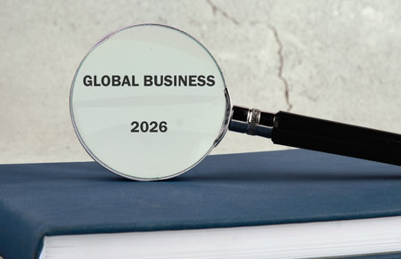 A magnifying glass focuses attention on the words GLOBAL BUSINESS and the year 2026. It rests upon a...