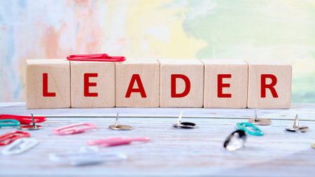 The word LEADER is spelled out with wooden blocks. Paper clips and thumbtacks are scattered around the blocks, adding to the compositions visual appeal.の写真素材