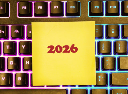 Yellow sticky note with 2026 written on it lies on a backlit keyboard with purple and blue keys. Focus on future planning and technology.の写真素材