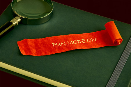 A bright orange scroll announcing FUN MODE ON unfurls across a dark green notebook. A magnifying...