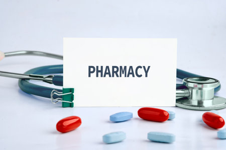 Several pills are scattered around a stethoscope. A card reading Pharmacy is held up by a clip next to medical equipment, symbolizing healthcare and treatment options.の写真素材