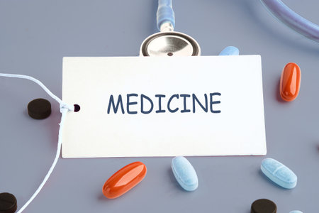 Pills of various sizes and colors sit near a card with the word MEDICINE written on it. A stethoscope is present, suggesting healthcare or a medical theme.の写真素材