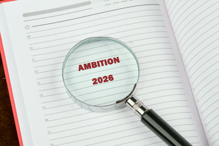An open diary is being inspected with a magnifying glass. The glass highlights the word Ambition and the year 2026, signaling a focus on future plans and goals.の写真素材