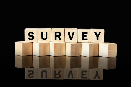 Wood blocks spell out the word SURVEY against a black background. The blocks reflect on the surface below, highlighting the importance of data collection and analysis.の写真素材