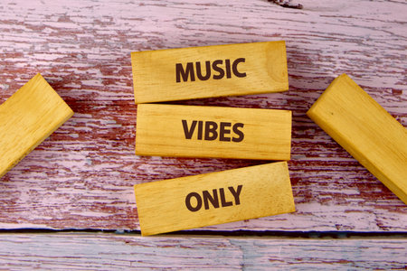 Wooden blocks with the words MUSIC VIBES ONLY are arranged creatively on a textured wooden surface. The scene evokes feelings of creativity and relaxation.の写真素材
