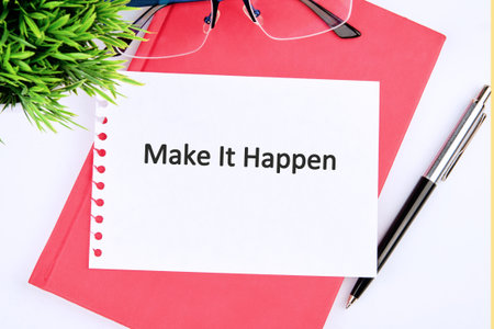 Arrangement shows a motivational message on paper, sitting on a journal. Eyeglasses, a pen, and a small plant complete the scene, suggesting a focus on productivity and positive action.の写真素材