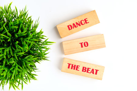Colorful wooden blocks spell out dance to the beat next to fresh green foliage, inviting everyone to...
