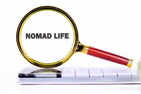 A magnifying glass highlights the words nomad life on a smartphone, symbolizing the exploration and excitement of a flexible, mobile lifestyle in todays world.の写真素材