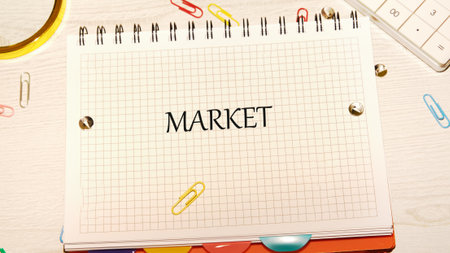 A creative writing space features the word MARKET prominently on a grid notebook, surrounded by colorful paperclips and a calculator, inviting new thoughts and business ventures.の写真素材