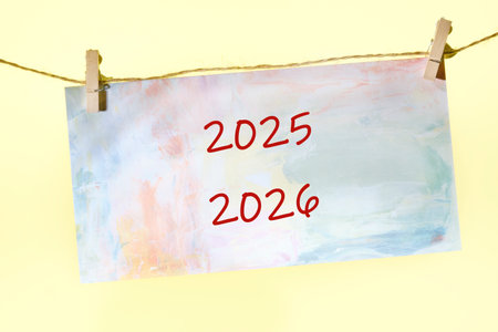 A colorful piece of art displays the years 2025 and 2026, creatively painted and hung with clothespins on twine, evoking a sense of optimism and future plans.の写真素材