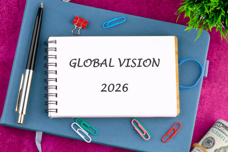 A spiral notebook opened to reveal the title Global Vision 2026, surrounded by office supplies and a hint of cash, symbolizing preparation and forward-thinking.の写真素材