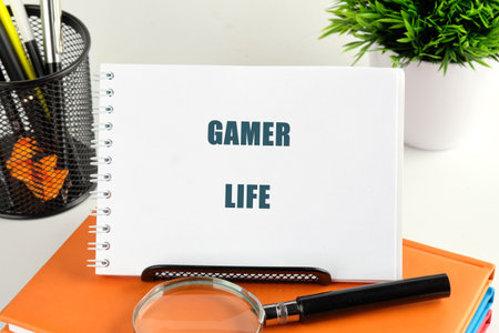 A notepad displays the words Gamer Life, surrounded by colorful stationery and a magnifying glass, capturing the creativity of gaming enthusiasts in a bright workspace.の写真素材