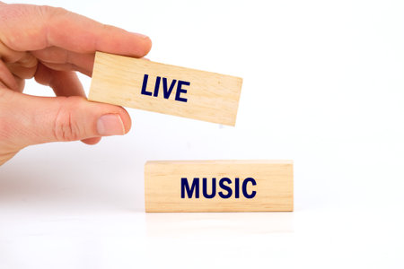 Hands are holding wooden blocks that read live and music, symbolizing the excitement and energy of live performances in a creative setting, perfect for music lovers.の写真素材