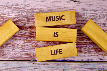 Wooden blocks are placed on a faded pink background, spelling out the meaningful phrase that music is life.の写真素材