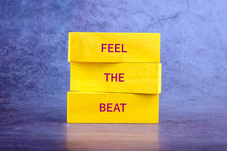 Three yellow wooden blocks are stacked on each other. The words FEEL THE BEAT are printed across the blocks, suggesting the pulse and rhythm of music.の写真素材