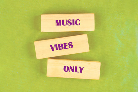 Three wooden blocks rest on a light green surface. The words MUSIC , VIBES , and ONLY are printed in purple on each of the blocks.の写真素材