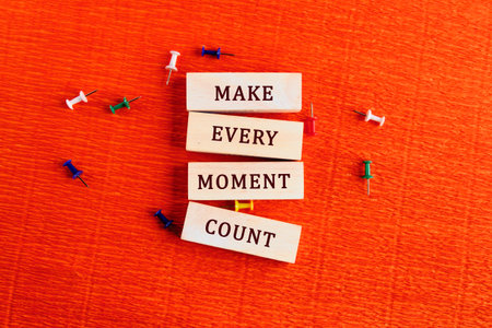 Colorful wooden blocks display the inspiring message make every moment count on a bright orange...