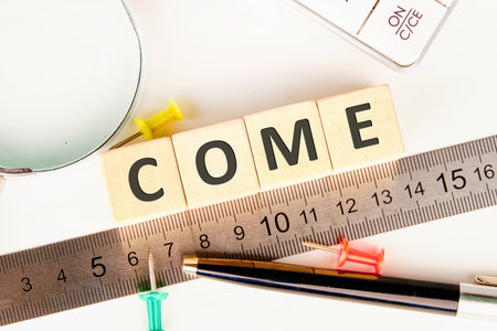 A bright workspace features wooden blocks spelling the word come. A ruler lies nearby along with...