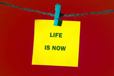 A bright yellow sticky note hanging on a blue string against a red background, boldly stating the...