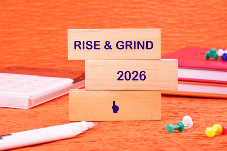 Bright orange setting highlights wooden blocks that bear the message rise and grind alongside the...