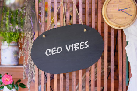 A sign reading CEO vibes hangs in an inviting outdoor area. The rustic charm is enhanced by flowers and a natural wooden clock, reflecting a cozy atmosphere of motivation and success.の写真素材