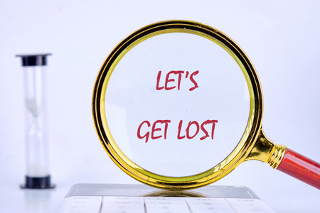 A magnifying glass focusing on the phrase Lets Get Lost invites adventure and exploration. Behind it, an hourglass symbolizes the fleeting nature of time, encouraging spontaneity.の写真素材