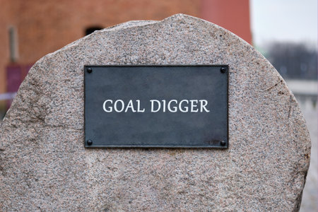 A textured granite stone features a dark plaque that says GOAL DIGGER in white capital letters. The...