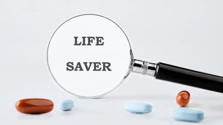 A magnifying glass focuses on the words LIFE SAVER. Several colorful pills are scattered around the base of the glass, all against a stark white backdrop.の写真素材