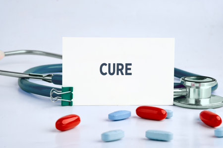 A white card displaying the word CURE is nestled among red and blue pills and a stethoscope,...