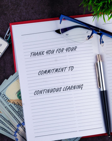 A notebook displays a thank you message, adorned with a pen, glasses, money, and a plant,...