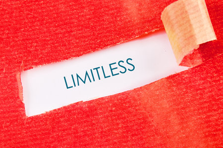 Red paper is torn open to reveal a crisp white background. Bold teal text proclaims the word Limitless. One can see possibilities beyond barriers and ceilings.の写真素材