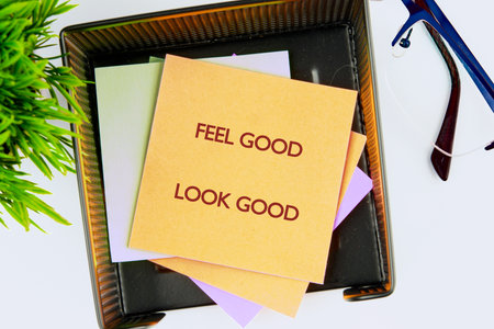 Golden sticky note Feel Good Look Good rests on colorful papers in a black desk organizer. A green...