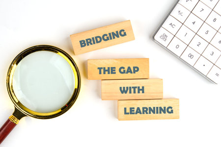 Four wooden blocks declare BRIDGING THE GAP WITH LEARNING on a clean white surface.