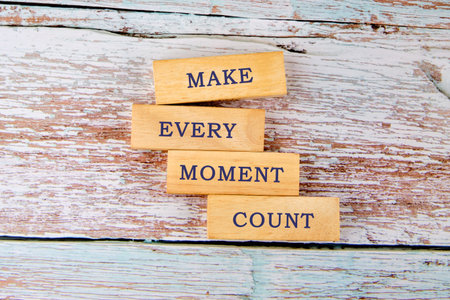 Four wooden blocks are arranged vertically, spelling the words Make Every Moment Count.