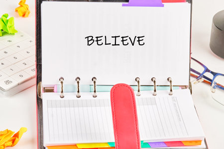BELIEVE on a planner page, surrounded by colorful tabs and office essentials on a white desk, inspires daily purpose