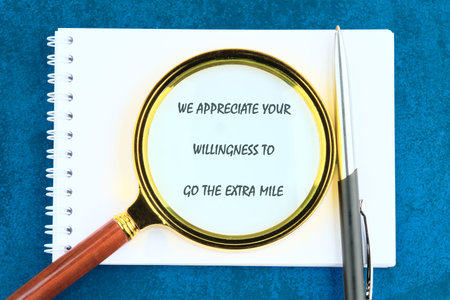 Blue surface: spiral notebook, magnifying glass on hard work message, sleek pen. Celebrates excel...