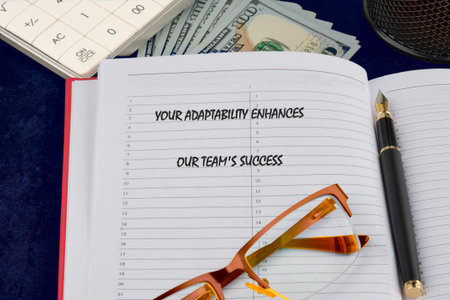 Mantra on planner: Adaptability for team success. Financial tools, pen, glasses. Diligent work...