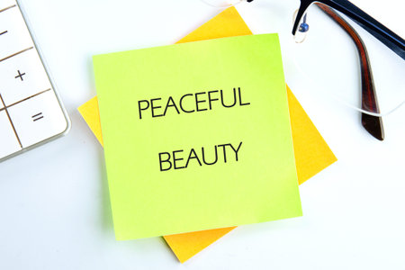 Green PEACEFUL BEAUTY note on yellow, on white desk with calculator glasses, sparks calm work...