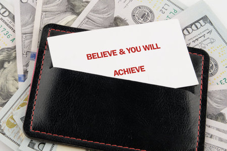 A powerful quote, Believe you will achieve, emerges from a dark leather wallet, gracefully placed...