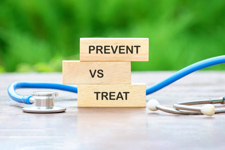 Three wooden blocks clearly spelling Prevent vs Treat are stacked beside a blue stethoscope on a...