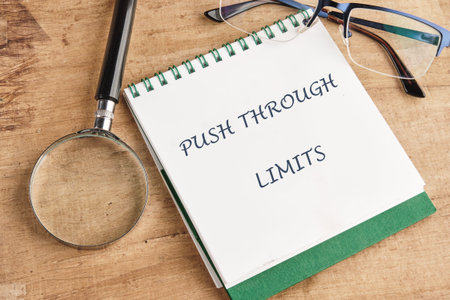Motivational words PUSH THROUGH LIMITS fill a notebook, placed on a cozy wooden table with...