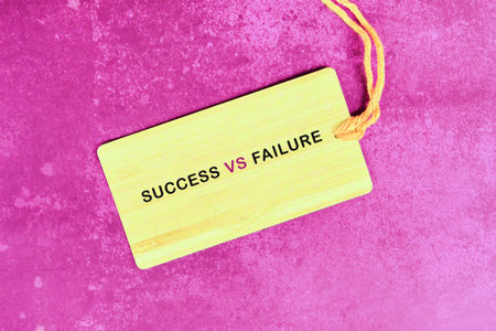 A light yellow wooden tag displaying SUCCESS VS FAILURE in contrasting fonts rests on a rich,...